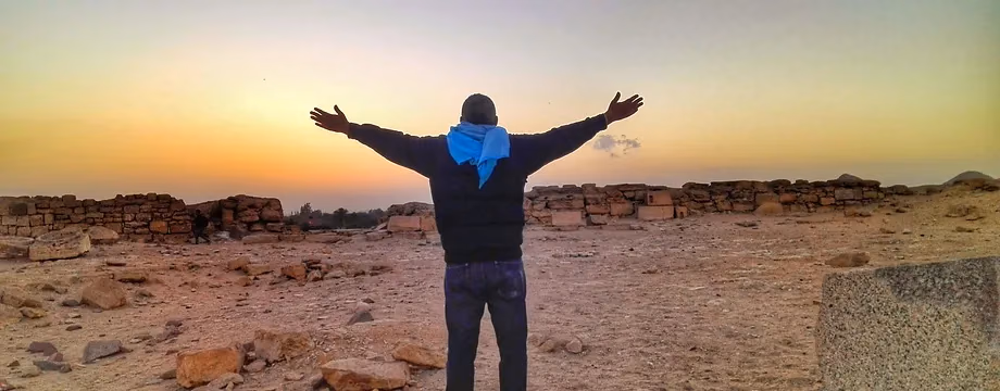 Arms wide at sunset over the Saqqara desert