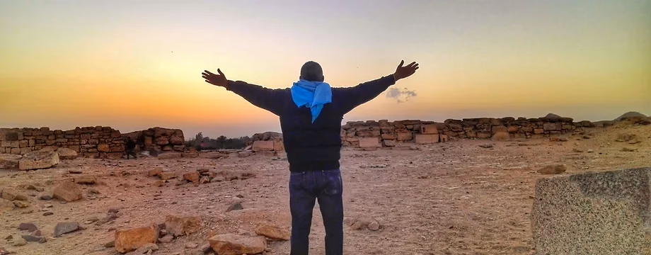 Arms wide at sunset over the Saqqara desert