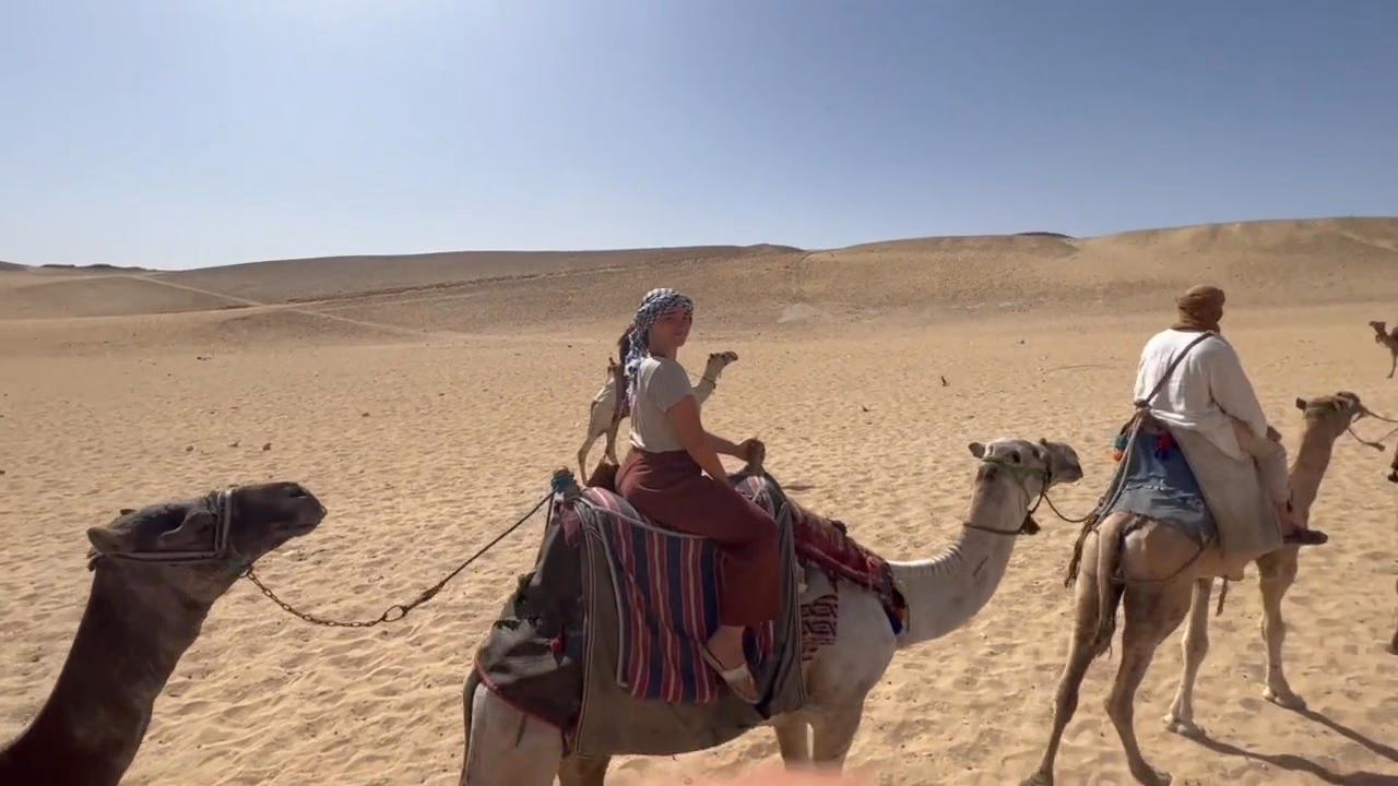 Guests riding camels across the open desert