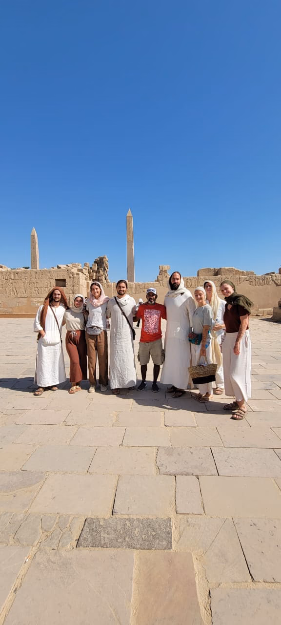 Guests in white linen before the obelisk at Karnak
