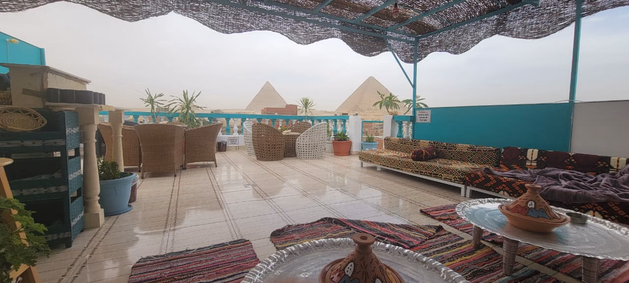 The shaded rooftop majlis with cushions and a pyramid view