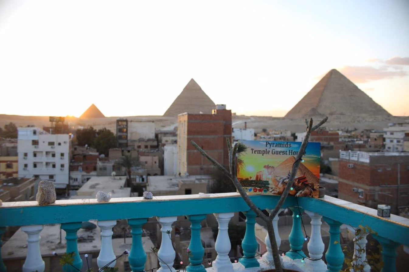 The three pyramids at sunset from the rooftop, with the Pyramids Temple Guest House sign