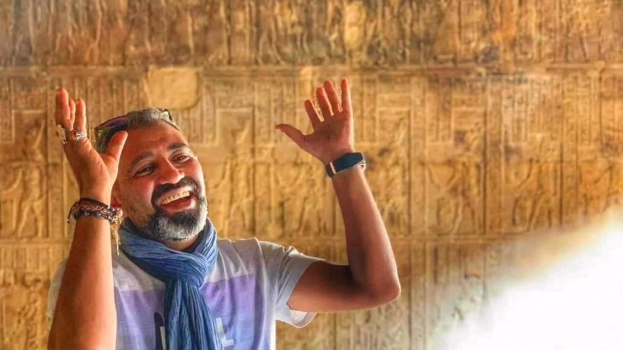 Rami, arms raised, inside a temple